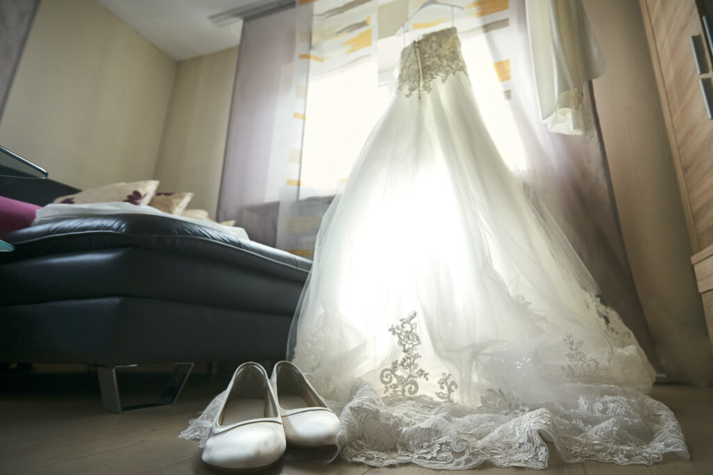 Hochzeitsbilder Idee: Das Brautkleid im Gegenlicht des Fensters vom Boden aus mit den Brautschuhen fotografiert.