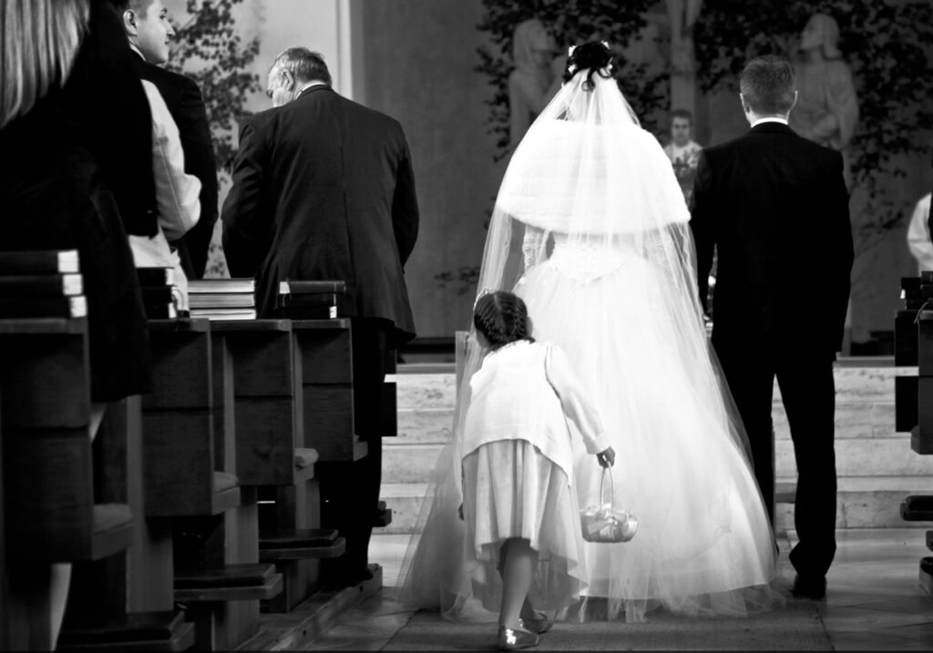 Brautpaar zieht in Kirche ein, Kind zupft Kleid zurecht