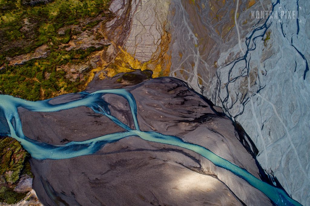 Drohnenfoto eines hellblauen Flussbettes durch eine graue Landschaft