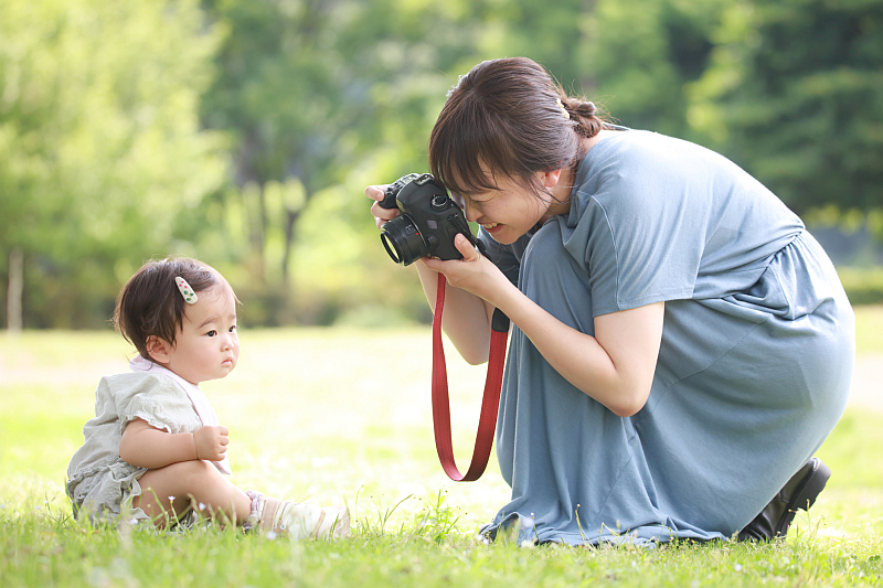 Babyfotografie: Mutter fotografiert ihr Baby im Park